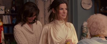 Movie still from “The Proposal” (2009), directed by Anne Fletcher – A woman in a cream colored dress holding a banana; Medium shot, Over the shoulder angle