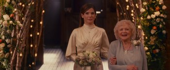 Movie still from “The Proposal” (2009), directed by Anne Fletcher – A woman holding a bouquet of flowers in her hand; Medium shot, Over the shoulder angle