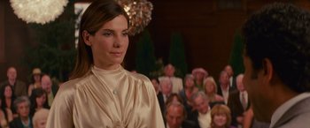 Movie still from “The Proposal” (2009), directed by Anne Fletcher – A woman standing in front of a group of people; Close Up shot, Over the shoulder angle