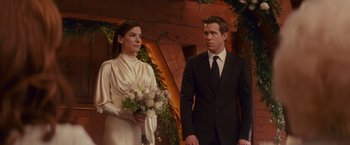 Movie still from “The Proposal” (2009), directed by Anne Fletcher – A man and a woman standing next to each other holding a bouquet; Medium shot, Over the shoulder angle