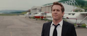 Movie still from “The Proposal” (2009), directed by Anne Fletcher – A man in a suit and tie standing in front of a hangar; Close Up shot, Low angle