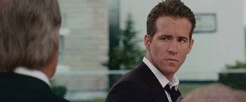 Movie still from “The Proposal” (2009), directed by Anne Fletcher – A person wearing a suit and tie; Close Up shot, Over the shoulder angle