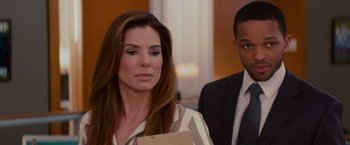 Movie still from “The Proposal” (2009), directed by Anne Fletcher – A man and a woman standing next to each other in a room; Close Up shot, Over the shoulder angle