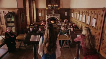 Movie still from “Ella Enchanted” (2004), directed by Tommy O'Haver – A group of people sitting at tables in front of a fireplace; Wide shot, Over the shoulder angle