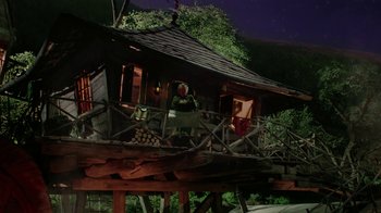 Movie still from “Ella Enchanted” (2004), directed by Tommy O'Haver – A woman standing on a porch of a wooden house at night; Extreme Wide shot, Low angle