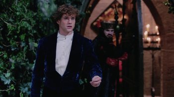 Movie still from “Ella Enchanted” (2004), directed by Tommy O'Haver – A man in a blue velvet jacket standing in front of another man in a black suit; Medium shot, Over the shoulder angle