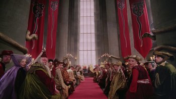 Movie still from “Ella Enchanted” (2004), directed by Tommy O'Haver – A group of people sitting on a red carpet in front of a large window; Extreme Wide shot, High angle