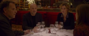 Movie still from “Elle” (2016), directed by Paul Verhoeven – A man and a woman sitting at a table with wine glasses; Medium shot, Over the shoulder angle