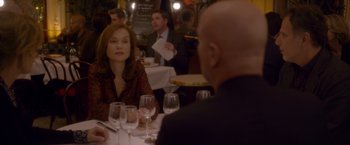 Movie still from “Elle” (2016), directed by Paul Verhoeven – A woman sitting at a table in front of a man; Medium shot, Over the shoulder angle