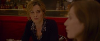 Movie still from “Elle” (2016), directed by Paul Verhoeven – A woman sitting at a table in front of another woman; Close Up shot, Over the shoulder angle