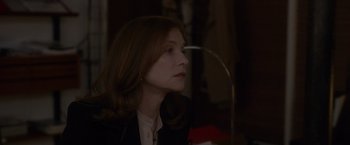 Movie still from “Elle” (2016), directed by Paul Verhoeven – A person sitting in a room; Close Up shot, Over the shoulder angle