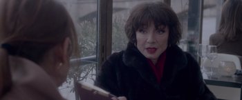 Movie still from “Elle” (2016), directed by Paul Verhoeven – A woman sitting in front of a window holding a book; Close Up shot, Over the shoulder angle