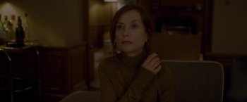 Movie still from “Elle” (2016), directed by Paul Verhoeven – A woman sitting on a couch in a living room; Close Up shot, Over the shoulder angle