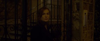 Movie still from “Elle” (2016), directed by Paul Verhoeven – A woman standing in front of an iron gate; Close Up shot, Low angle