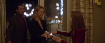 Movie still from “Elle” (2016), directed by Paul Verhoeven – A woman handing a package to another woman in front of a window at night; Medium shot, Over the shoulder angle