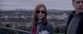 Movie still from “Elle” (2016), directed by Paul Verhoeven – A woman wearing sunglasses standing in front of a city; Close Up shot, Over the shoulder angle