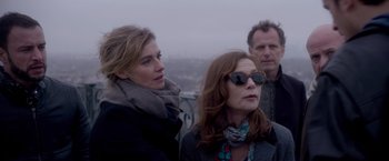 Movie still from “Elle” (2016), directed by Paul Verhoeven – Two women and a man looking out over a city; Medium shot, Low angle