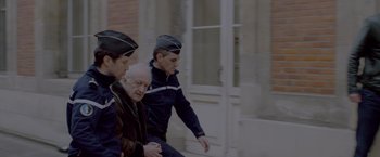 Movie still from “Elle” (2016), directed by Paul Verhoeven – A group of men in uniform walking down a street; Medium shot, Low angle