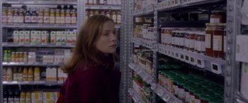 Movie still from “Elle” (2016), directed by Paul Verhoeven – A woman standing in front of shelves in a grocery store; Close Up shot, Over the shoulder angle