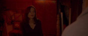 Movie still from “Elle” (2016), directed by Paul Verhoeven – A woman in a black shirt is standing in front of a red wall; Close Up shot, Over the shoulder angle