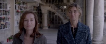 Movie still from “Elle” (2016), directed by Paul Verhoeven – Two women standing next to each other in front of a building; Medium shot, Low angle