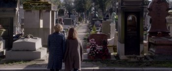 Movie still from “Elle” (2016), directed by Paul Verhoeven – Two women walking down a path in a cemetary; Wide shot, High angle