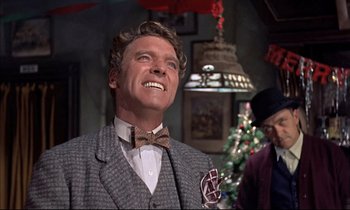 Movie still from “Elmer Gantry” (1960), directed by Richard Brooks – A man wearing a suit and bow tie in front of a christmas tree; Medium shot, Low angle