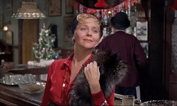 Movie still from “Elmer Gantry” (1960), directed by Richard Brooks – A woman in a red shirt holding onto a fur stole; Medium shot, Low angle