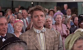 Movie still from “Elmer Gantry” (1960), directed by Richard Brooks – A man in a suit standing in front of a group of people; Medium shot, Low angle