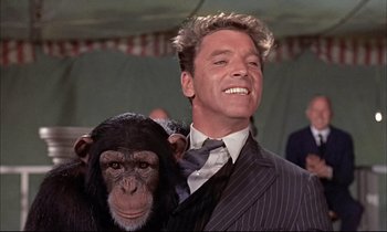 Movie still from “Elmer Gantry” (1960), directed by Richard Brooks – A man in a suit and tie holding a monkey; Close Up shot, Low angle