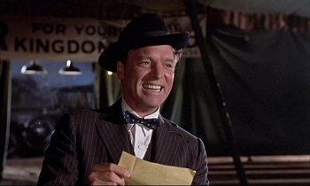Movie still from “Elmer Gantry” (1960), directed by Richard Brooks – A man wearing a suit and a hat holding a letter; Medium shot, Low angle