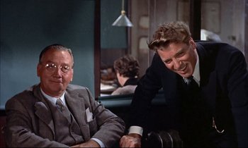 Movie still from “Elmer Gantry” (1960), directed by Richard Brooks – Two men in business suits sitting at a table; Medium shot, Over the shoulder angle