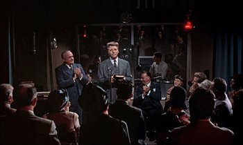 Movie still from “Elmer Gantry” (1960), directed by Richard Brooks – A group of people sitting in a room with microphones; Wide shot, Low angle
