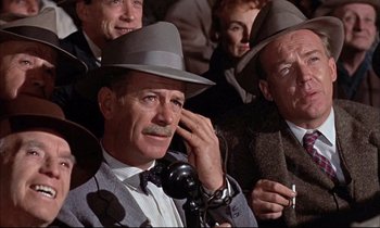 Movie still from “Elmer Gantry” (1960), directed by Richard Brooks – An older man wearing a hat while talking on a phone; Close Up shot, Low angle