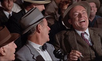 Movie still from “Elmer Gantry” (1960), directed by Richard Brooks – A group of men sitting in a crowd wearing hats and ties; Close Up shot, Over the shoulder angle