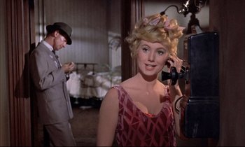 Movie still from “Elmer Gantry” (1960), directed by Richard Brooks – A woman in a pink dress talking on a phone; Medium shot, Low angle