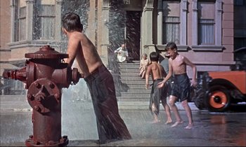 Movie still from “Elmer Gantry” (1960), directed by Richard Brooks – A group of young boys playing in the water from a fire hydrant; Wide shot, High angle