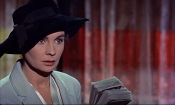 Movie still from “Elmer Gantry” (1960), directed by Richard Brooks – A woman in a black hat holding a stack of papers; Close Up shot, Over the shoulder angle
