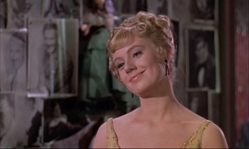 Movie still from “Elmer Gantry” (1960), directed by Richard Brooks – A woman in a yellow dress smiling for the camera; Close Up shot, Low angle