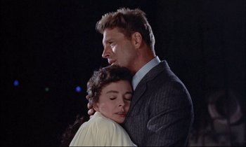 Movie still from “Elmer Gantry” (1960), directed by Richard Brooks – A man and a woman embracing each other in front of a dark background; Close Up shot, Low angle
