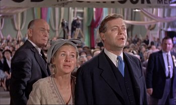 Movie still from “Elmer Gantry” (1960), directed by Richard Brooks – A man and a woman standing next to each other in a crowd; Medium shot, Low angle