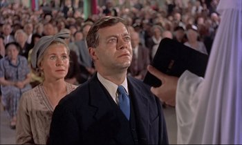 Movie still from “Elmer Gantry” (1960), directed by Richard Brooks – A man in a suit and tie in front of a group of people; Medium shot, Low angle