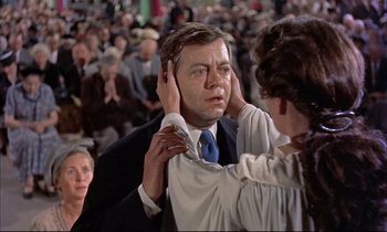 Movie still from “Elmer Gantry” (1960), directed by Richard Brooks – An older man is being put on a tie by an older woman in a crowd; Close Up shot, Over the shoulder angle