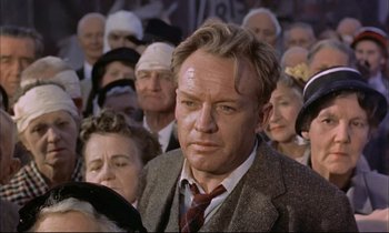 Movie still from “Elmer Gantry” (1960), directed by Richard Brooks – A man in a suit and tie in front of a group of people; Close Up shot, Low angle