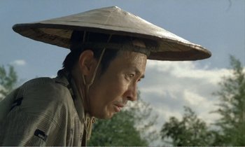 Movie still from “Empire of Passion” (1978), directed by Nagisa Ôshima – A man with a hat on his head looking to his left; Close Up shot, Low angle