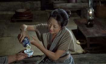 Movie still from “Empire of Passion” (1978), directed by Nagisa Ôshima – A woman is pouring a drink into a cup; Medium shot, High angle