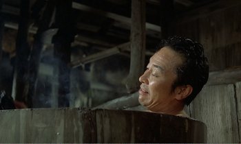 Movie still from “Empire of Passion” (1978), directed by Nagisa Ôshima – A man is taking a bath in a wooden tub; Medium shot, High angle