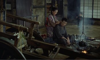 Movie still from “Empire of Passion” (1978), directed by Nagisa Ôshima – A man and a woman sitting on the ground in front of a fire pit; Wide shot, High angle
