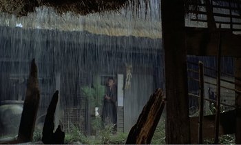 Movie still from “Empire of Passion” (1978), directed by Nagisa Ôshima – A man standing in front of a house in the rain; Extreme Wide shot, Low angle