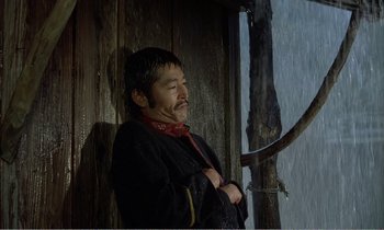 Movie still from “Empire of Passion” (1978), directed by Nagisa Ôshima – A man standing in front of a wooden wall; Medium shot, Low angle